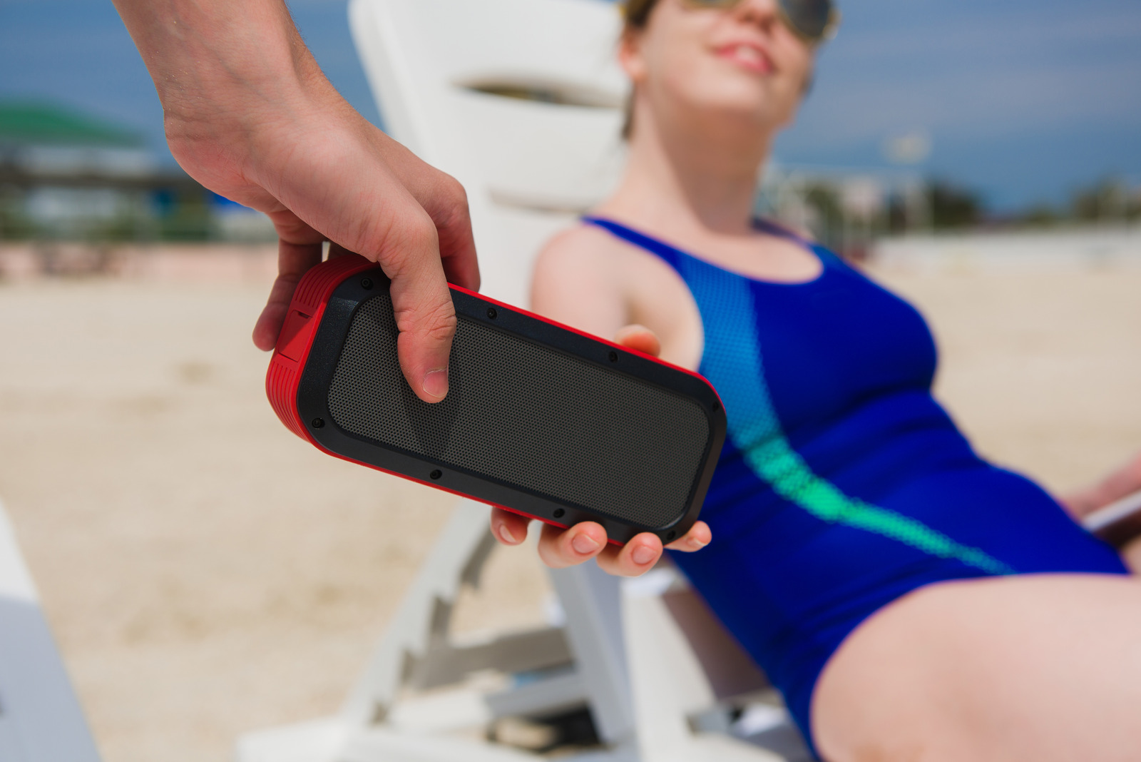 Man give to woman portable speaker. Bluetooth usb wireless red acoustic at beach party outdoors