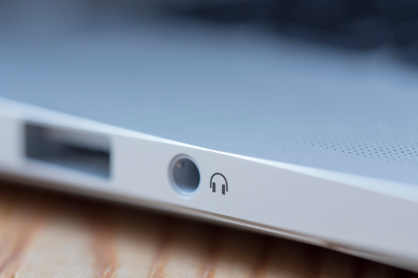 Shot of a headphone port on the side of a laptop. The headphone logo is in focus while the rest is blurred out.