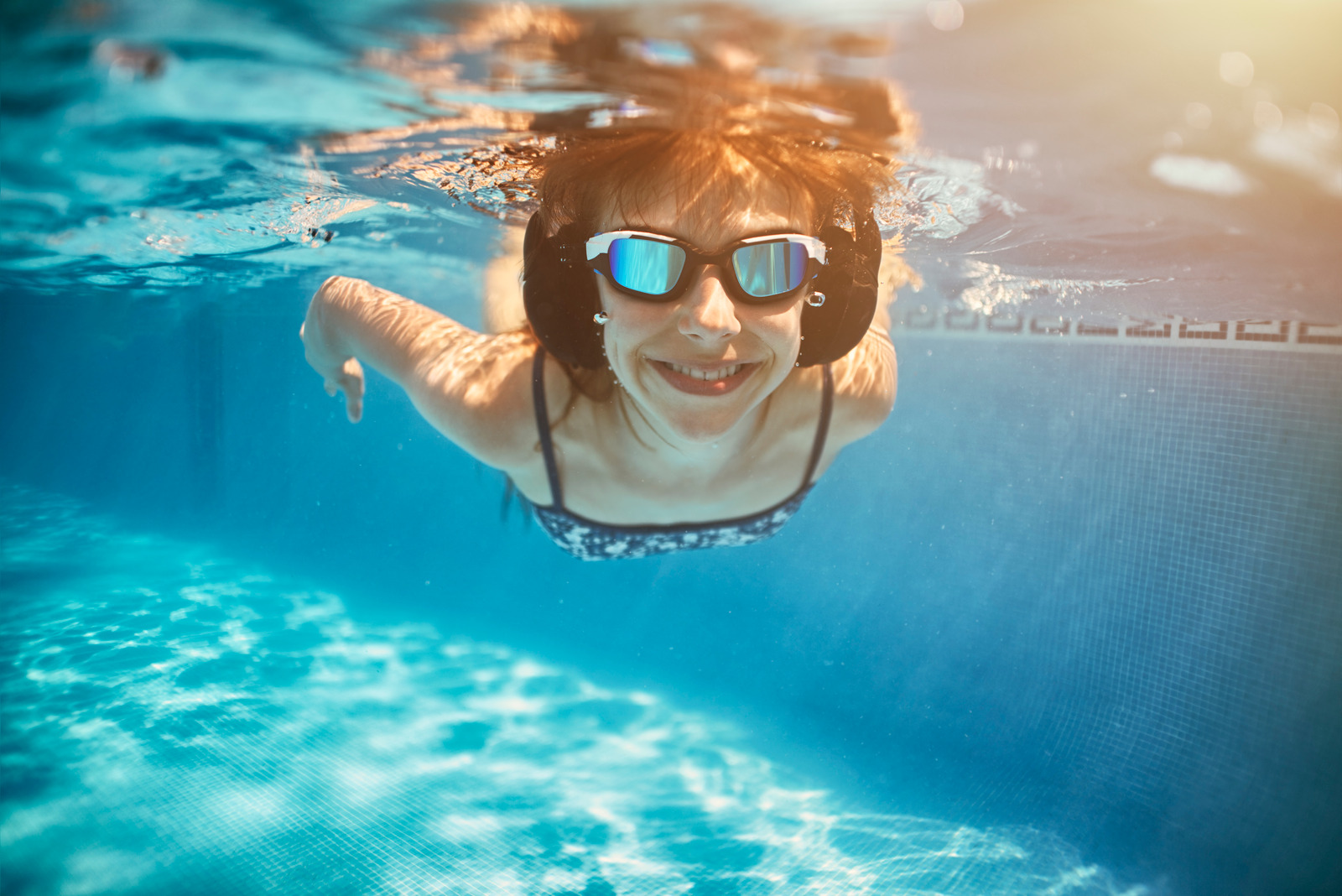 Teenage girl swimming underwater. The girl is wearing underwater headphones and listening to music.