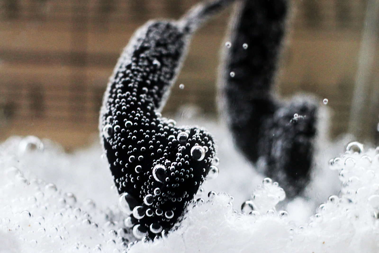 Black headphones in water with bubbles, sound
