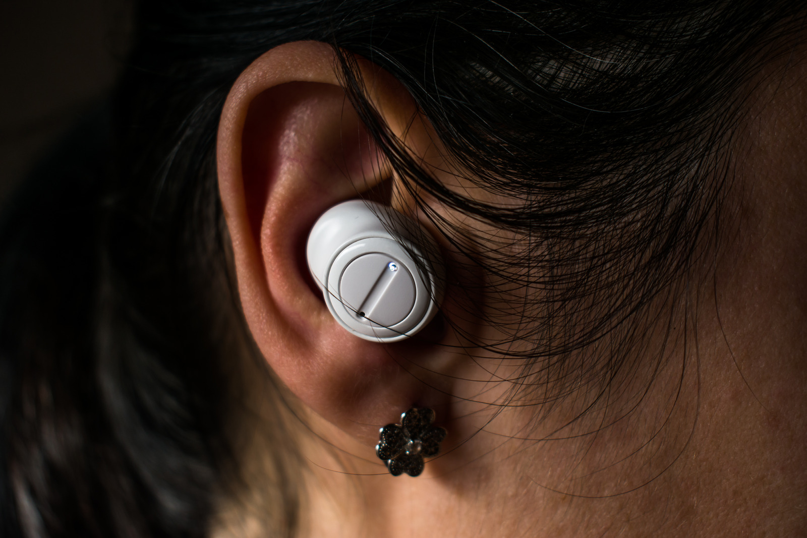 Woman ear with white wireless in-ear headphones