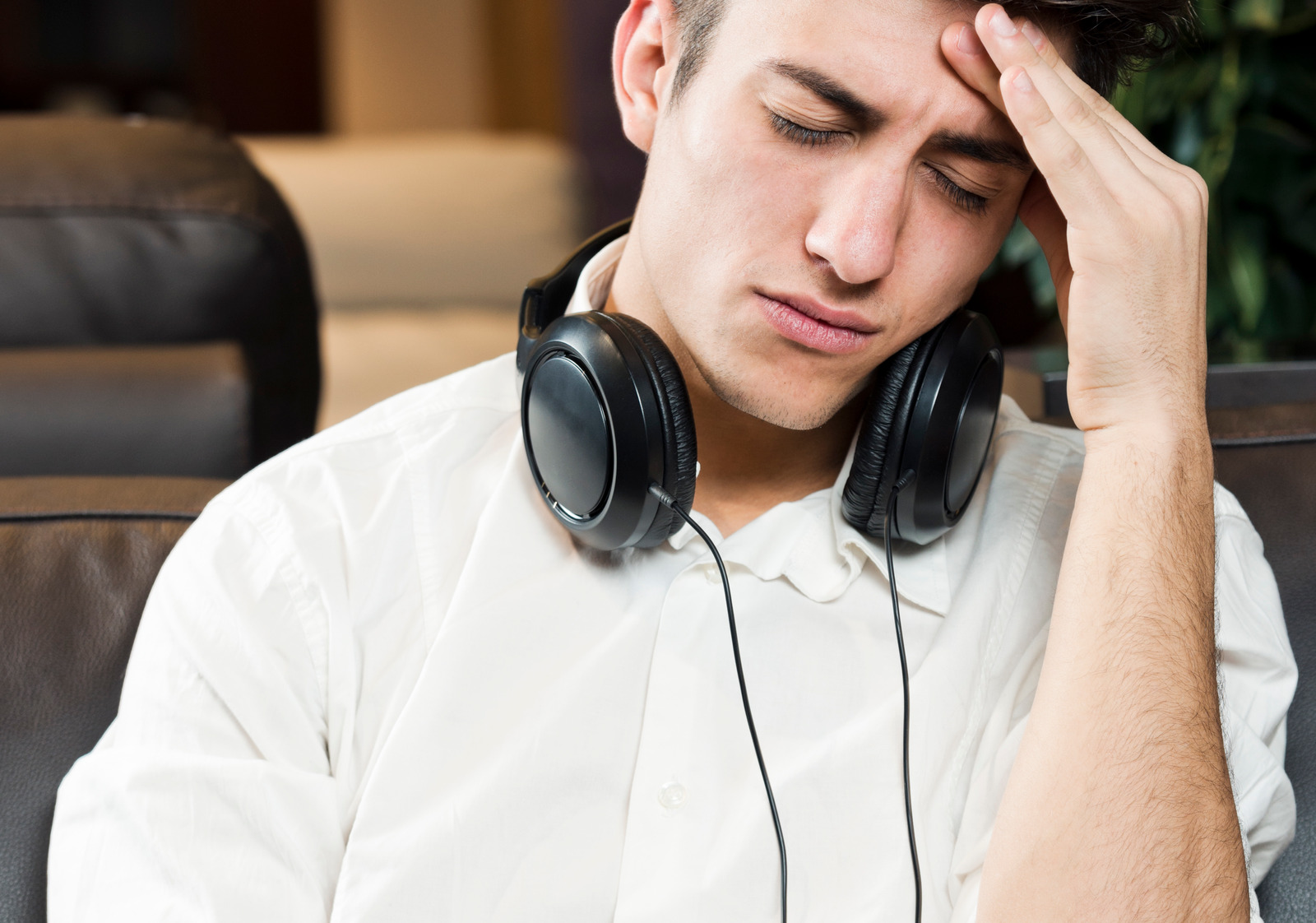 Upset man with headache and headphones