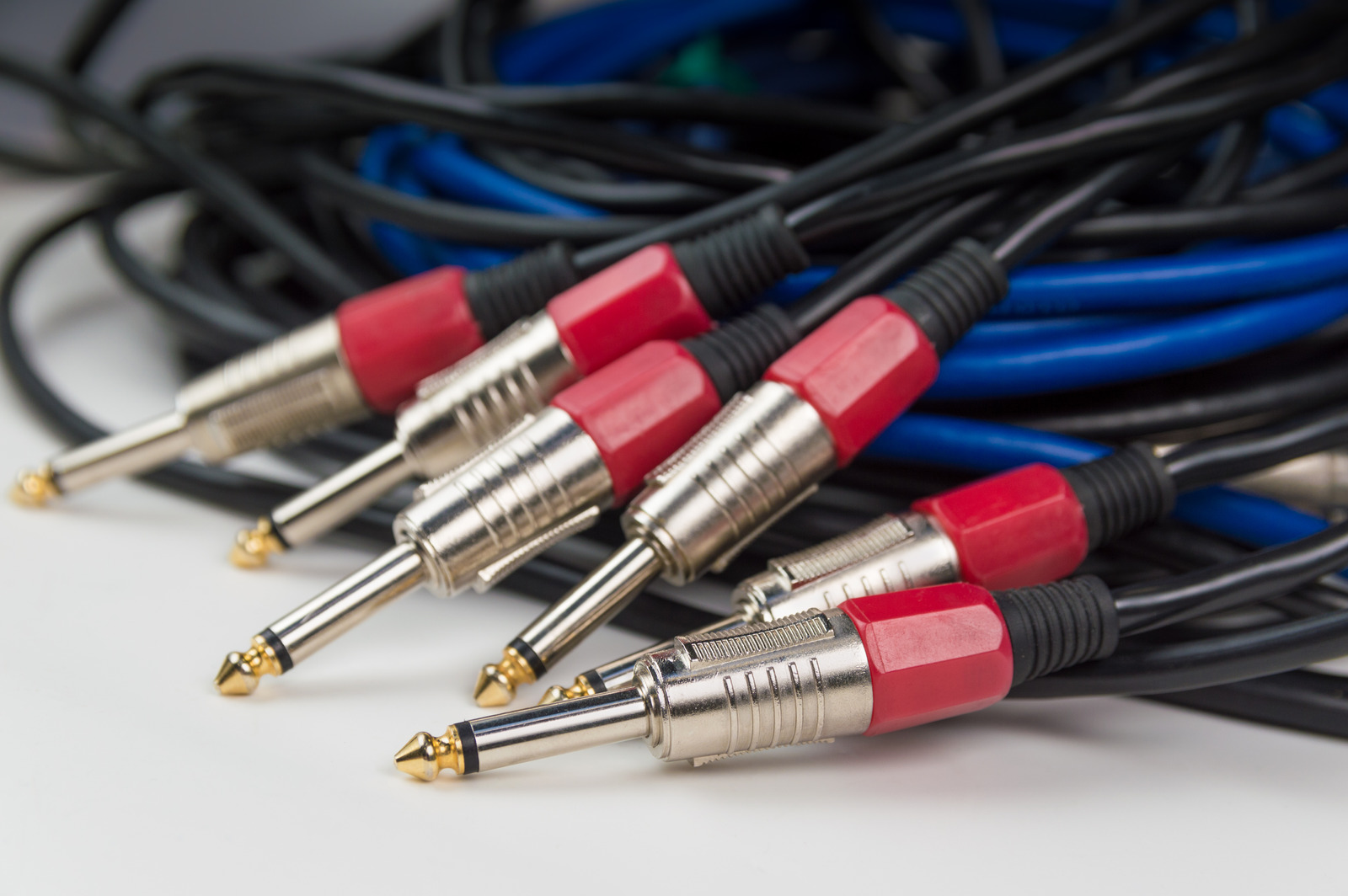 Blue and black audio cables with mono TRS connectors, lie on a white table.