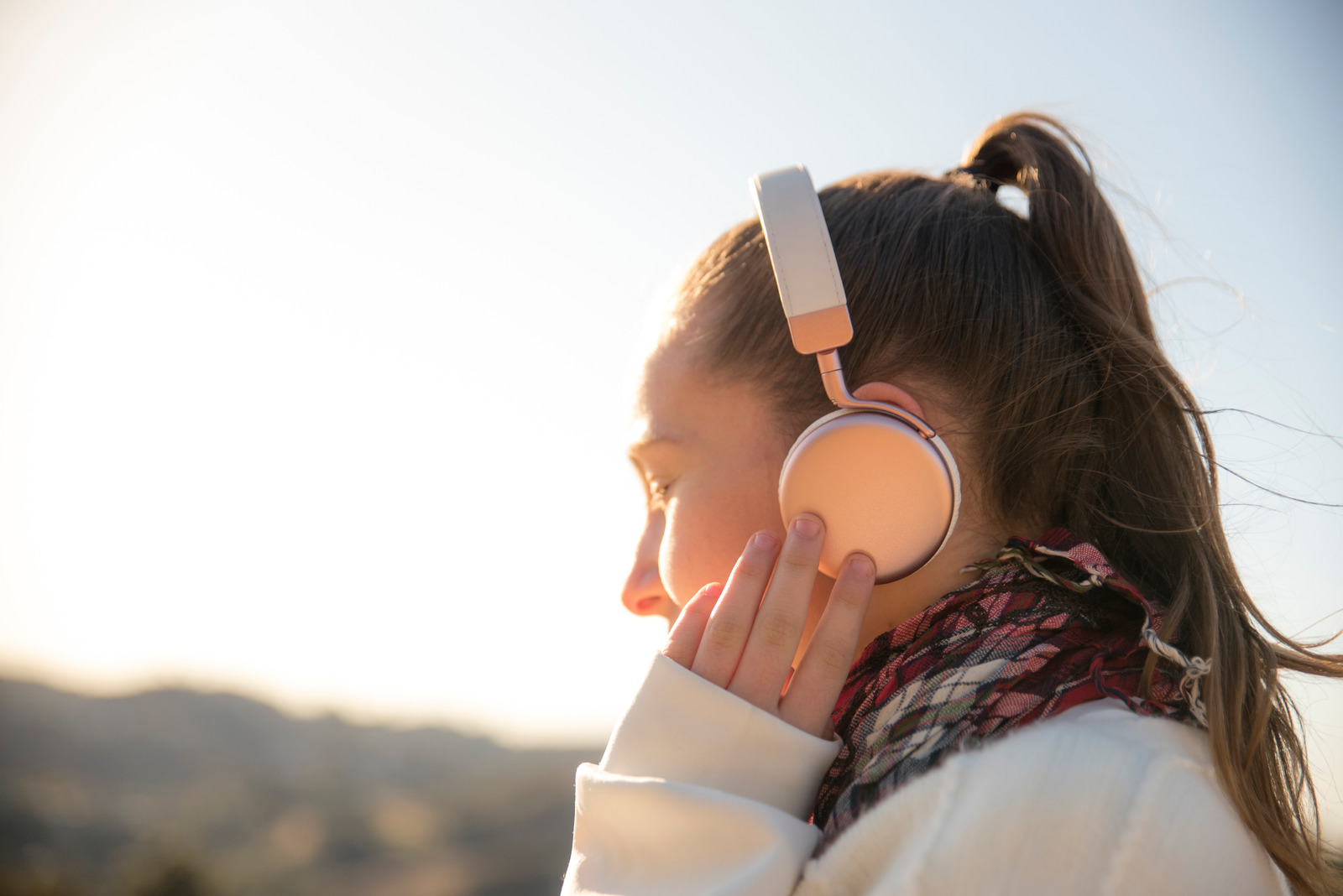 Girl wearing headphones outdoors.