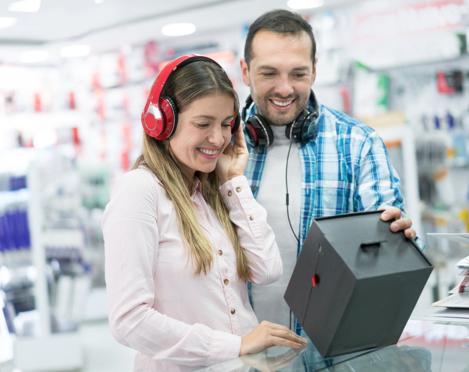 Casual young couple shopping for electronics at tech store and looking very happy
