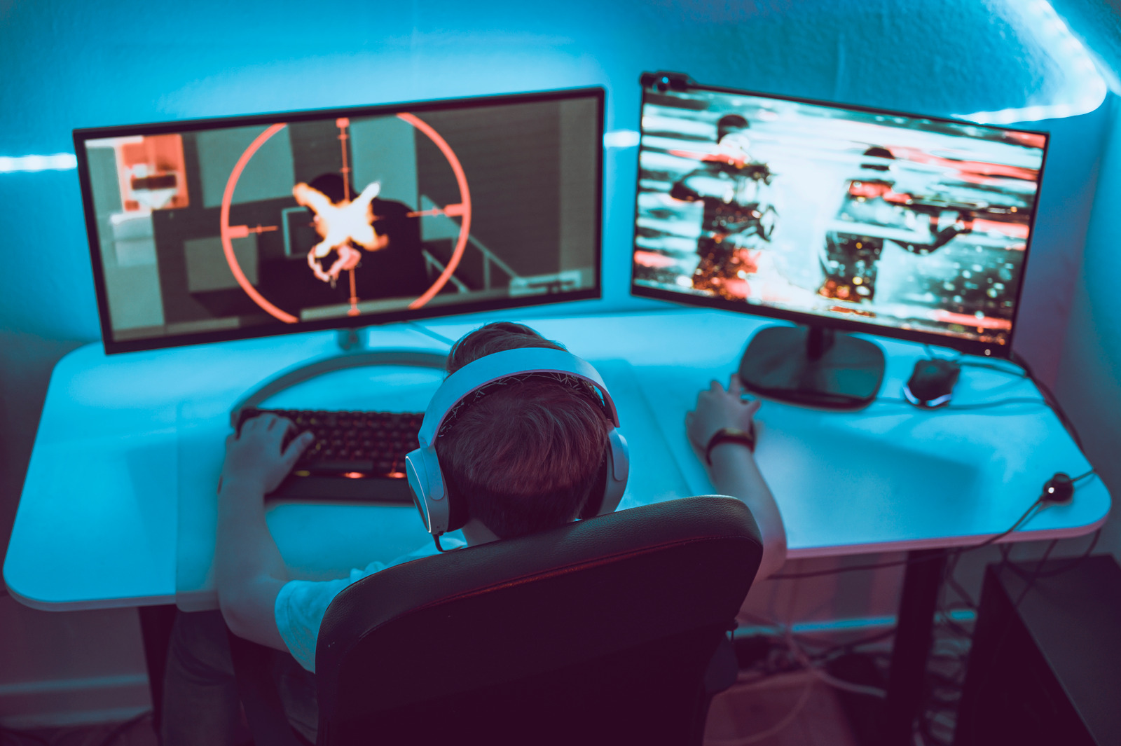 Boy sits in front of two monitors connected to a desktop gaming computer. 