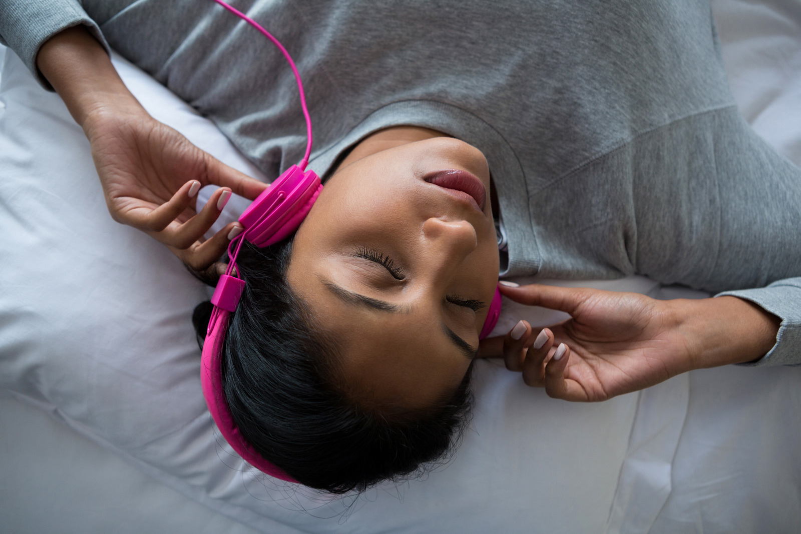 Young woman listening to music while sleeping on bed at home