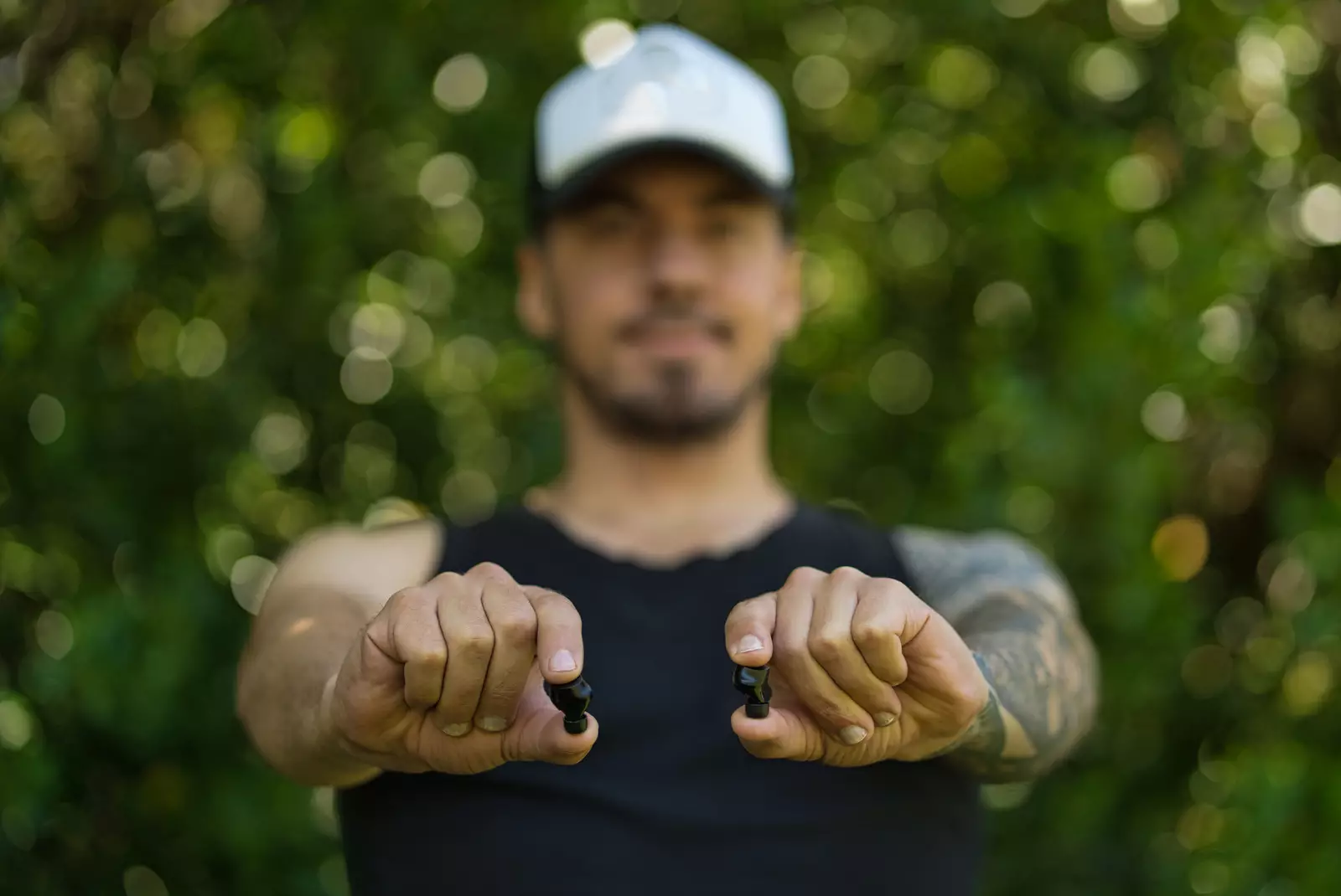 Young man holding wireless earbuds. Close up. Outdoor Background