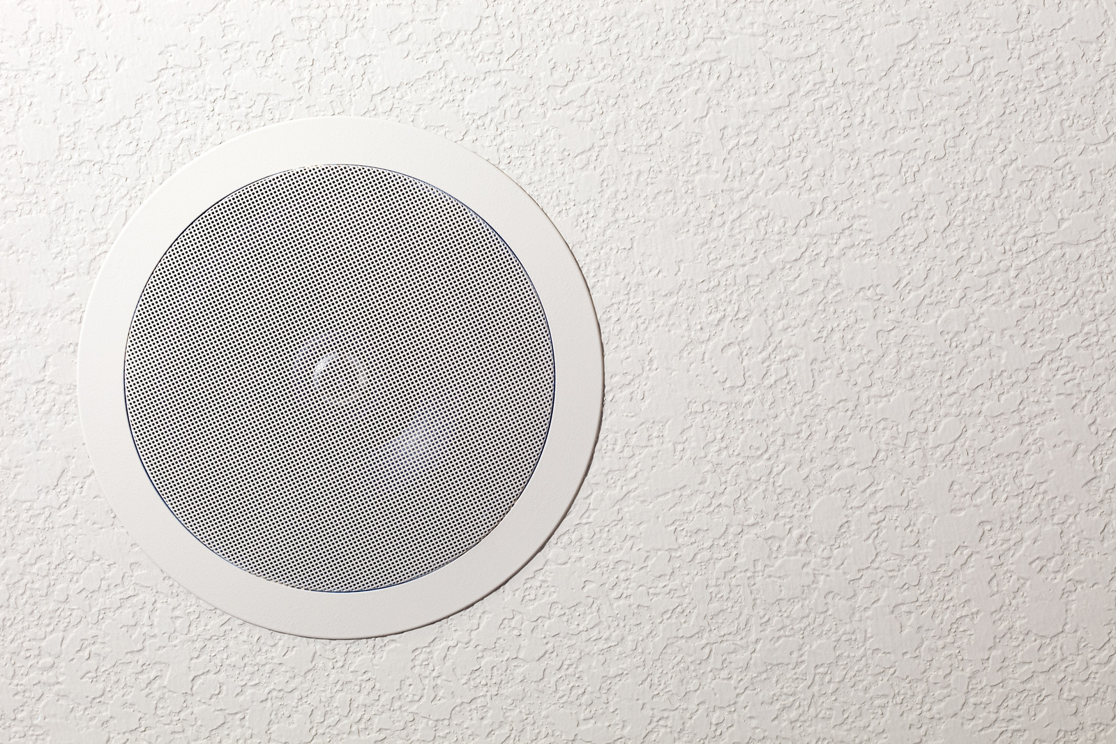 "A new in-ceiling residential surround sound speaker. Multiple speakers are mounted throughout the house, providing background audio entertainment."