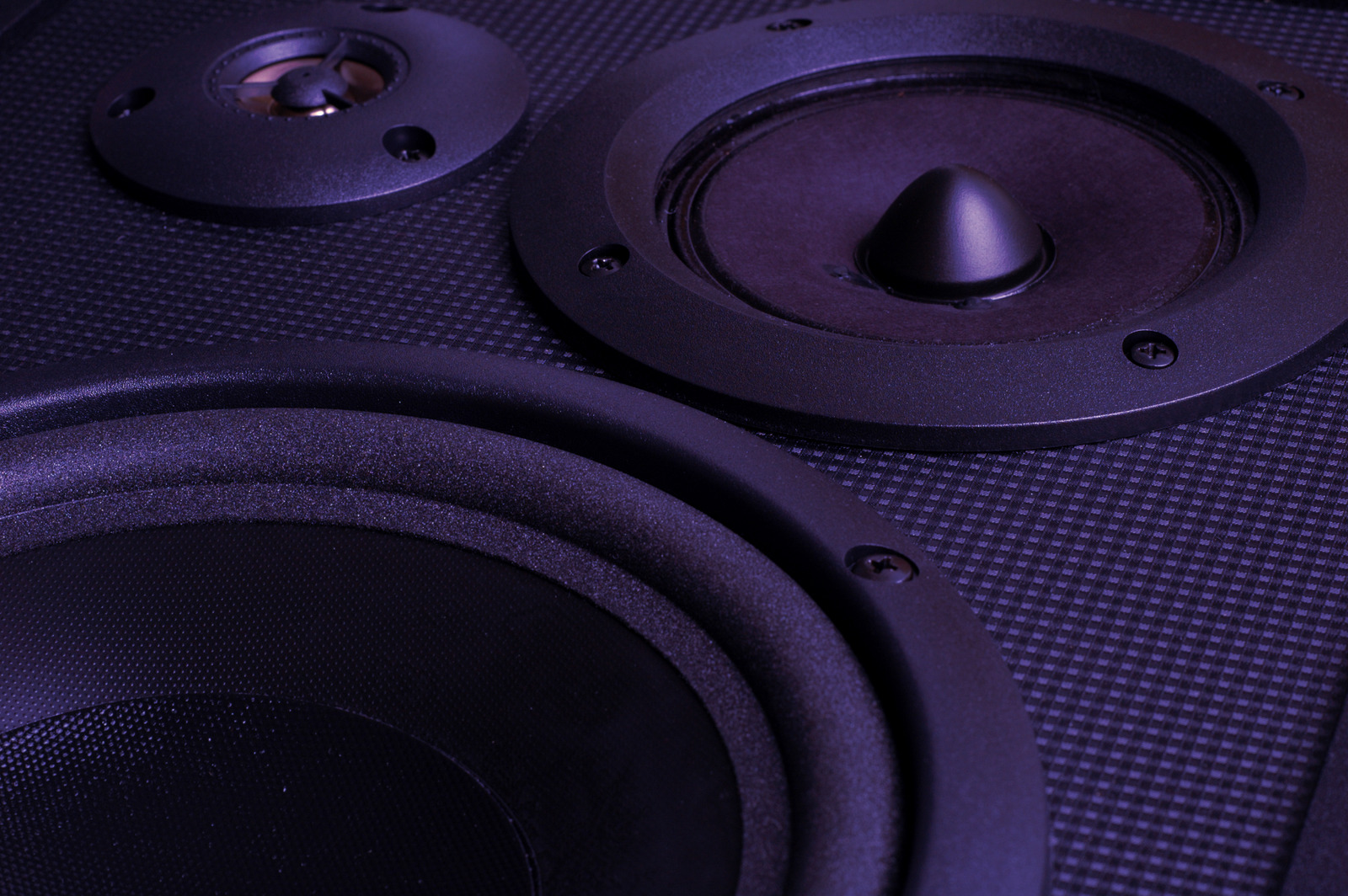 Closeup color photo of speakers in blue lighting with selective focus on the midrange speaker.http://www.ideabugmedia.com/istock/concert.jpg