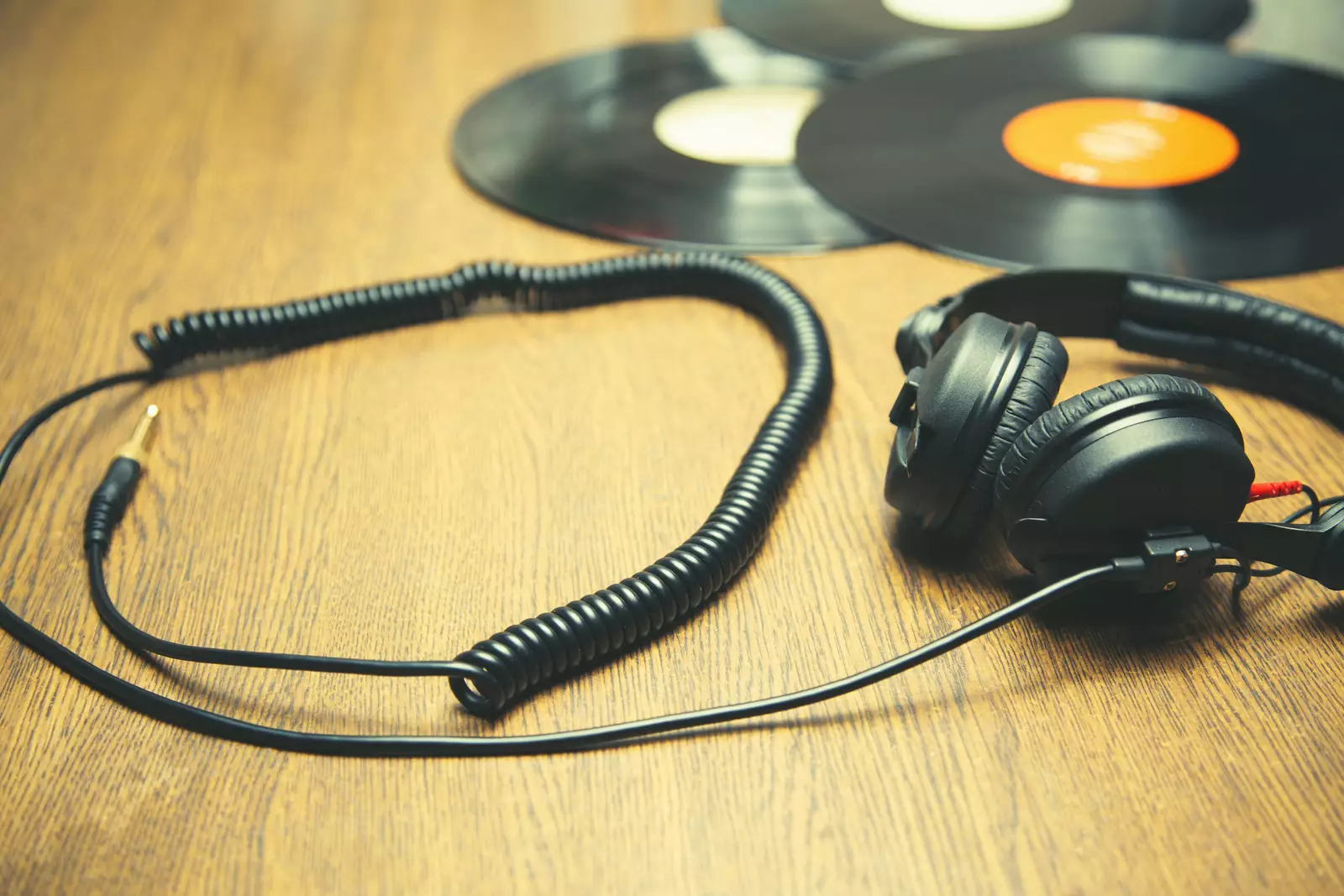Black Dj headphones and two Vinyl records on the wooden table.