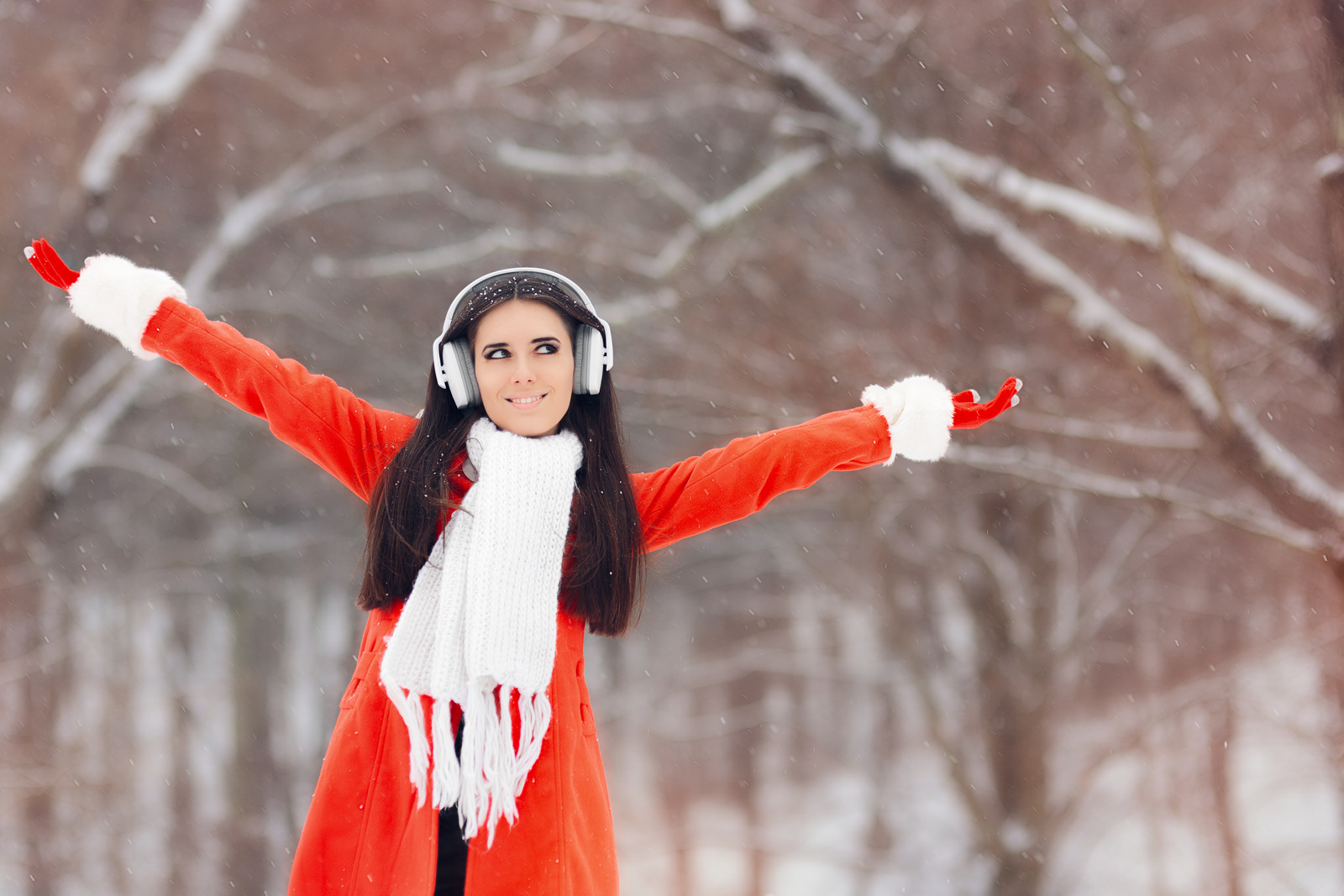 Smiling girl having fun in winter time listening to music with headphones